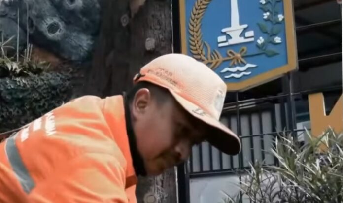 Kisah cerita petugas kebersihan saat gelar tidak menjamin pekerjaan. Setiap pagi, Andika (27) mengenakan seragam oranye menyala dan memanggul sapu lidi serta karung sampah.